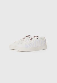 Zapatillas de lona blancas con un prominente logo "COLMAR", puntera redonda, cierre de cordones en el frente y suela de goma texturizada con acentos de diseño mínimos.