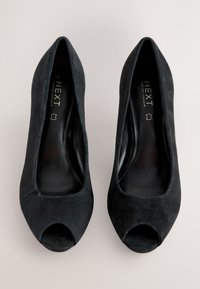 Czarne zamszowe szpilki z odkrytymi palcami, z ostro zakończonym przodem i gładką podszewką wewnętrzną. Charakteryzują się minimalistycznym designem i brakiem widocznych elementów metalowych.