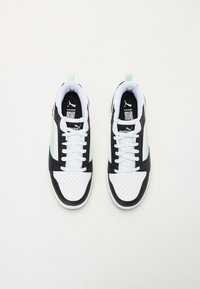 Pár černých, bílých a mint Puma tenisek s bílými tkaničkami, z pohledu shora na čistém bílém pozadí.