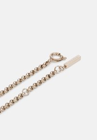 Srebrny naszyjnik łańcuszkowy z zaokrąglonymi ogniwami, z zapięciem typu lobster oraz prostokątną zawieszką wygrawerowaną napisem "Calvin Klein."