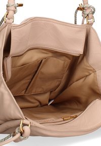 Intérieur d'un sac à main en cuir beige avec une texture lisse, comportant plusieurs compartiments, y compris une poche zippée et un revêtement en tissu.