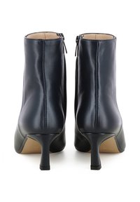 Stivali ankle in pelle nera con chiusura laterale a zip, tacco affusolato e texture liscia. L'interno è rifinito con una fodera beige.