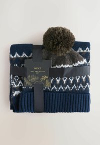 Tamsiai mėlynas megztas kepurės ir kaklaskarės rinkinys, su raštuotu dizainu baltos ir rudos spalvos, kepurėje yra rudos pom-pom, pritvirtinta juoda juostele.