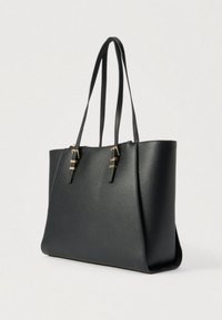 Čierna taška cez rameno z textúrovanej kože s dvoma tenkými ramennými pásikmi a detailmi zlatých prackov, zobrazená mierne z boku na jednoduchom pozadí.