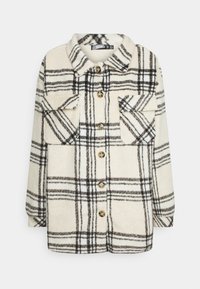 Krämfärgad och svart rutig jacka i mjukt, texturerat material. Har en krage, två framfickor och gula knappar. Knappstängning.