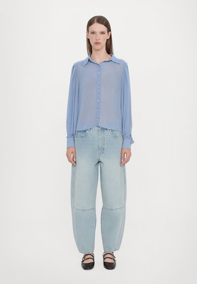 Light blue, sheer button-up shirt with long sleeves and a subtle shimmer, paired with high-waisted, loose-fitting light denim jeans.
