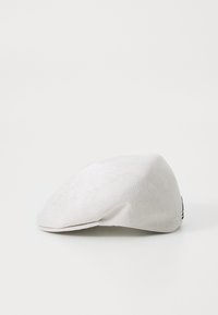 Căciulă albă cu o formă plată, confecționată dintr-un material țesut, având o textură netedă și un design conic. Detaliul cu eticheta pe lateral prezintă logo-ul brandului în negru.