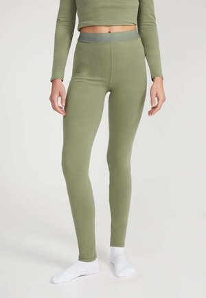 Grüne Leggings mit glatter Textur, hohem Bund und figurbetontem Design, kombiniert mit weißen Socken, auf einem neutralen Hintergrund gezeigt.