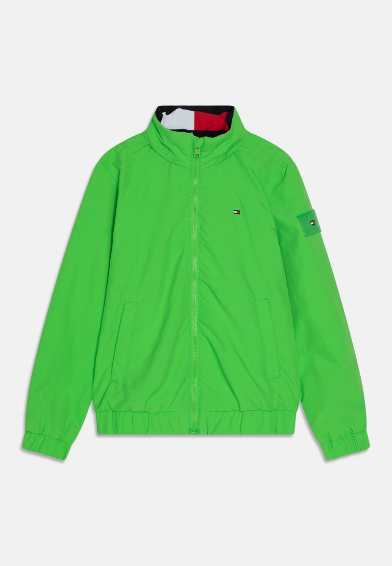 Vihreä kevyt takki, vetoketjulla edessä, joustavat hihansuut, puolikaulus, kaksi sivutaskua ja logopatch vasemmassa hihassa.