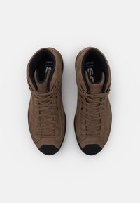 Brune fløyels høye sko med teksturert finish, med svarte gummisåler og grå snører, designet for holdbarhet og støtte.
