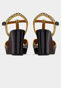 Μαύρα σανδάλια με ψηλό τακούνι, με κίτρινη λεπτομέρεια και γεωμετρικό σχέδιο στο λουράκι, με λεία υφή και τακούνια τύπου block.