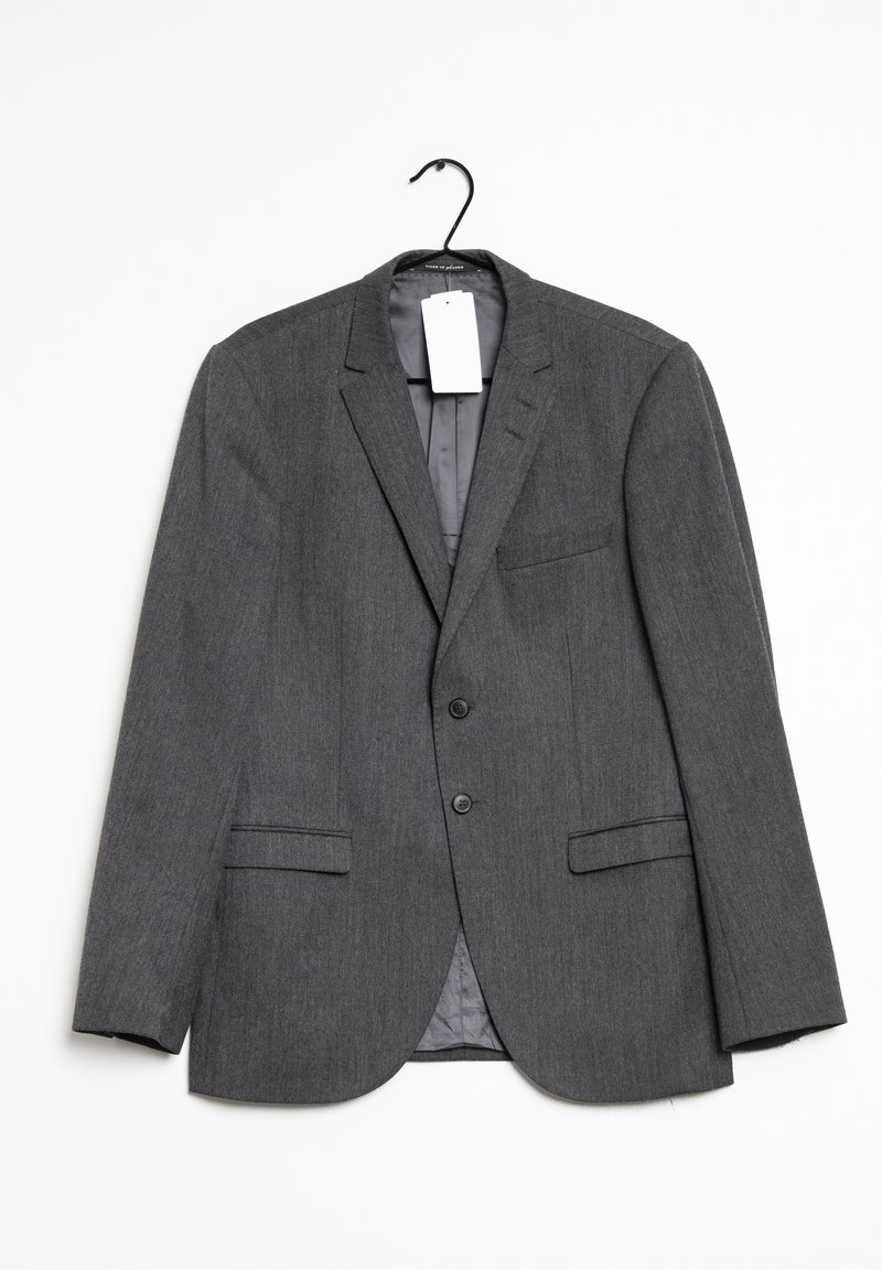 Grå blazer hängande på en krok. Har en skarp krage, två framfickor och en enda bröstficka. Tyget har en subtil struktur.