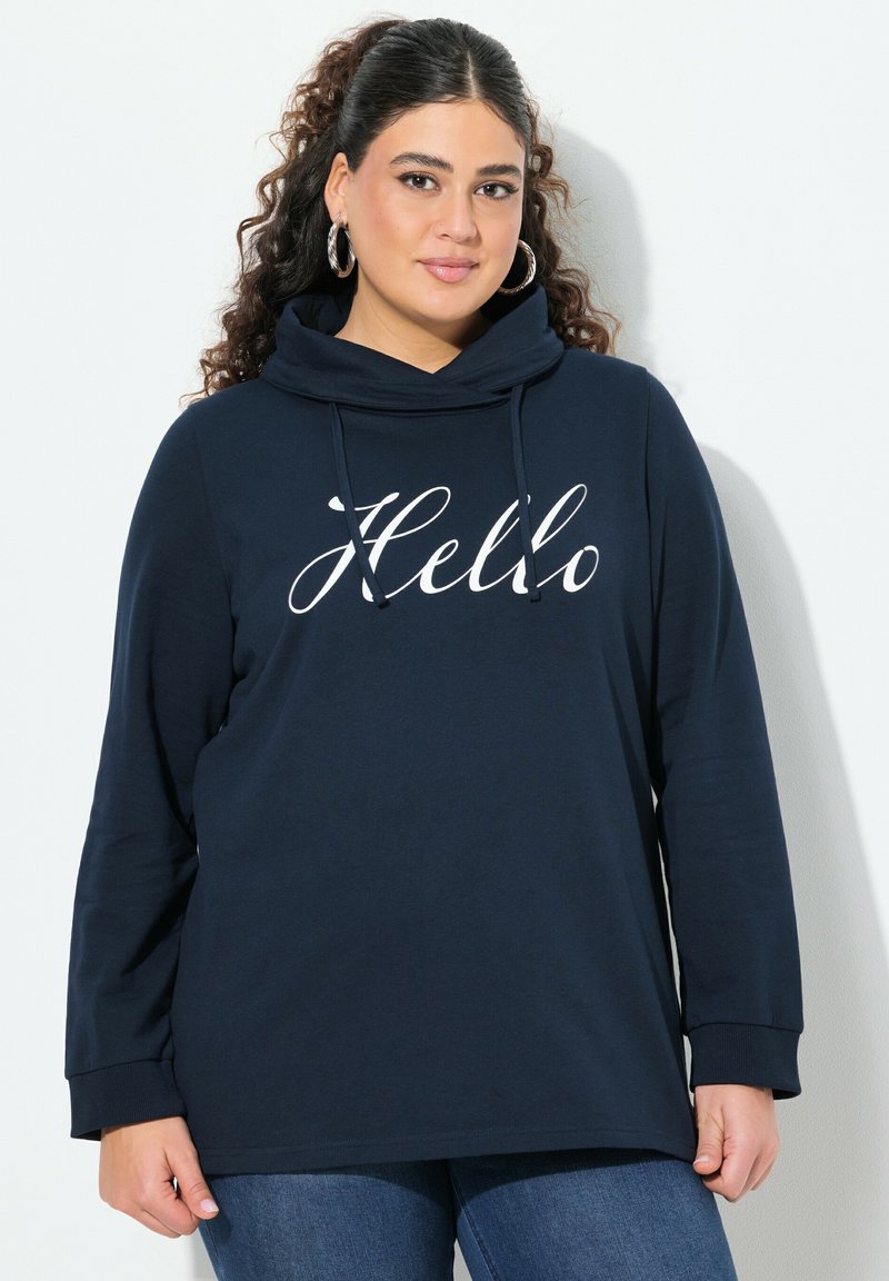 Felpa a maniche lunghe blu navy con collo a cappuccio e testo bianco "Hello". Tessuto morbido e vestibilità rilassata, abbinata a jeans in denim.