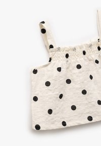 Bomulds tanktop med sorte prikker på en cremet baggrund, med elastisk smock ved halsudskæringen og justerbare stropper.