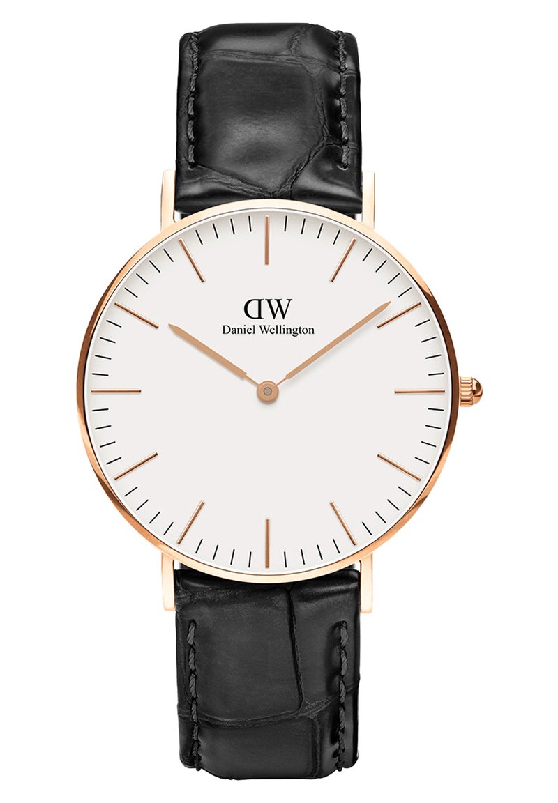 Runde Uhr mit weißem Zifferblatt, Gehäuse aus roségold, schwarzes Lederarmband mit Krokodilprägung und schlanken Stundenmarkierungen. Markenlogo auf 12 Uhr.