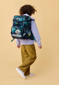 Rucksack mit dunkelblauem und grünem Außenmaterial, das ein Weltraumthema aufweist. Runde Form, mehrere Fächer und verstellbare Träger.