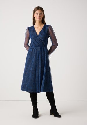 Blaues Wickelkleid mit floralem Muster, das lange durchsichtige Ärmel und eine taillierte Taille hat, ergänzt durch knielange schwarze Stiefel.