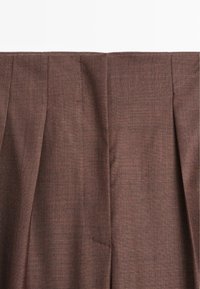 Brązowa tkanina tkana z widocznym teksturowanym wzorem, z fałdami i gładkim wykończeniem; ogólnie rzecz biorąc, ma zorganizowany i dopasowany design.