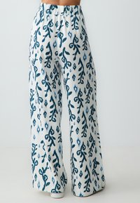 Pantalon large blanc avec un motif floral et en diamant bleu, doté d'une taille élastique et d'un tissu léger et doux.
