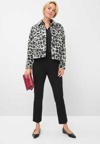 Luipaardprint, faux fur jas met zwarte knopen, gecombineerd met een zwart shirt en pinstripe broek. Houdt een bordeauxrode clutch vast en draagt zwarte flats.