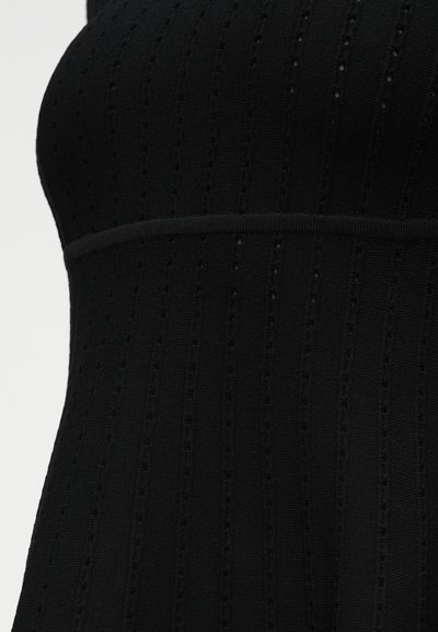 Κοντινή λήψη μαύρου ribbed πλεκτού υφάσματος με κάθετο μοτίβο με τρύπες και οριζόντια ραφή.