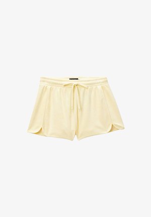 Shorts doux en tissu éponge jaune pâle avec ceinture élastique et cordon réglable, ourlets latéraux arrondis pour un usage décontracté.