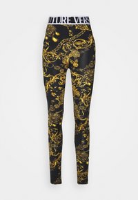 Leggings mit schwarzem Grund und einem goldenen, kunstvollen Muster, aus dehnbarem Material, mit einem weißen, gebrandeten Bund.