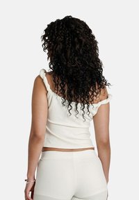 Witte geribde tanktop met geknutselde schouderbanden, aansluitend ontwerp en textiele stof, gecombineerd met een bijpassende onderkant in een naadloze stijl.
