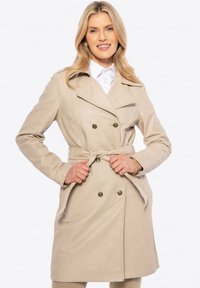 Trench coat beige con design doppiopetto, ampi revers e cintura. Presenta due tasche laterali e una texture liscia.
