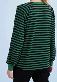 Grün- und schwarzgestreiftes Langarmshirt mit lockerer Passform. Mit Rundhals und gerafften Bündchen für zusätzliche Textur.