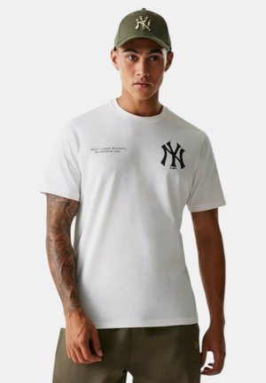 Camiseta blanca de algodón con el logo negro de los New York Yankees. Acompañada de una gorra verde con el logo bordado y visera curvada.