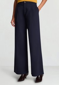 Marineblaue Hosen mit weitem Bein, schmaler Passform, hoher Taille, vorderen Falten und einem goldenen Knopf als Akzent, aus glattem, leichtem Stoff gefertigt.