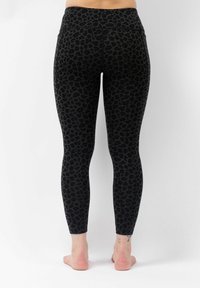 Zwarte leggings met een luipaardprint, gemaakt van rekbaar materiaal. Kenmerken zijn een hoge tailleband en een gladde, gestructureerde oppervlakte.
