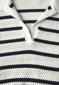 Strick-Polohemd mit weißen und navyblauen horizontalen Streifen, aus einem atmungsaktiven strukturierten Stoff und mit einem V-Ausschnitt-Kragen.