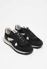 Black and gray lace-up sneakers with white accents, mesh and suede textures, and cushioned soles positioned side by side on white background.