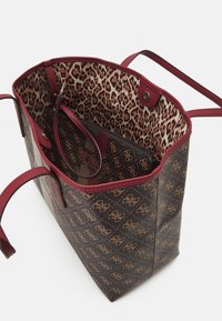 Brązowa i czerwona torba tote z monogramem, z wnętrzem w leopardzim wzorze, otwarta u góry, z dołączoną dopasowaną zasuwaną saszetką w środku.