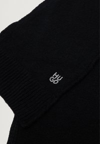 Maglione nero realizzato in morbido tessuto, con polsini a coste e un piccolo logo ricamato in argento sulla manica.