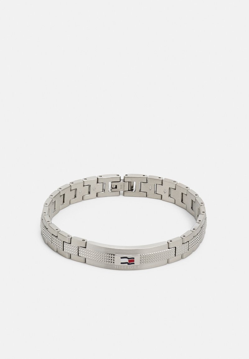 Bracelet en métal argenté avec un design entrelacé, mettant en valeur un centre texturé et un accent de logo subtil. Fini poli lisse. Fermoir ajustable.