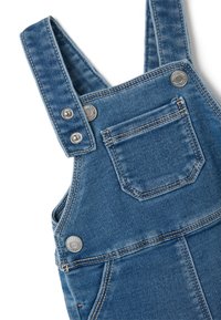 Denim salopettes in lichtblauw met verstelbare banden, zilveren drukknoopjes en een voorkantzak. Beschikt over een traditionele rechte snit.