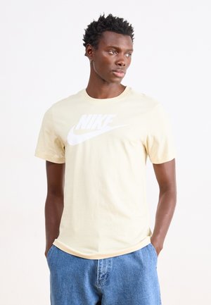 T-shirt di cotone giallo chiaro con un grande logo Nike bianco, scollatura rotonda e maniche corte. Vestibilità casual con una texture morbida.