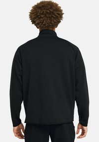 Černý svetr s vysokým límcem, dlouhými rukávy a volným střihem. Měkká textura, žádné viditelné vzory ani akcenty. Uniformní design ze zadní strany.