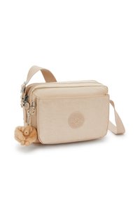 Beige canvas crossbody bag with a textured surface, zipper closure, a front pocket, and a fluffy charm attached to the zipper pull.