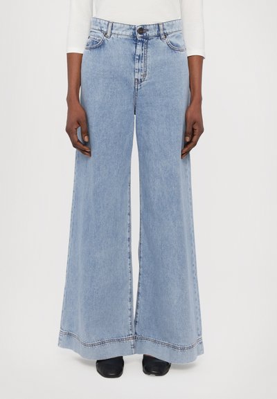 Jeans large en denim bleu clair, avec une taille haute, des poches avant et un ourlet droit avec des détails de couture.