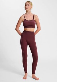 Bordeaux sports-bh med ribbet tekstur og justerbare stropper, kombineret med højttaljede leggings med kontrasterende sidesømme.