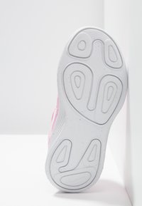 Růžová sportovní bota s texturovaným svrškem, která má bílou gumovou podrážku s výrazným vzorem a zakřivenými okraji.