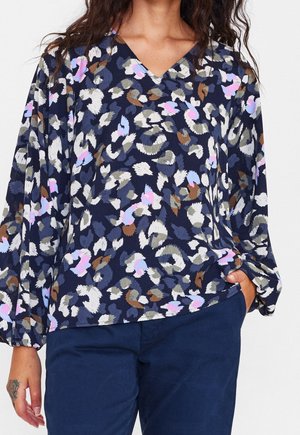 Marineblauwe blouse met een V-hals, voorzien van een veelkleurig abstract bladpatroon in wit, roze, blauw en bruin. Zacht materiaal en een losse pasvorm.