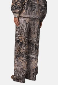 Camouflage-print relaxte broek in aardetinten met een patroon van schors en bladeren. Gemaakt van zachte stof met een losse pasvorm.