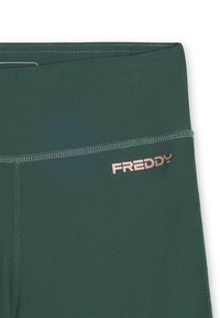 Leggings verde scuro realizzati in un materiale liscio, con una vita cucita e un logo "FREDDY" in rosa oro sul lato.