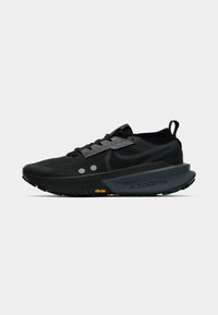 Black athletic shoe with mesh upper, textured laces, and a cushioned sole featuring a visible ZoomX logo and Vibram accent.