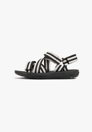 Sandalen mit Riemen aus einem schwarz-weiß gestreiften Stoff-Obermaterial, verstellbaren Riemen und einer flexiblen schwarzen Sohle.